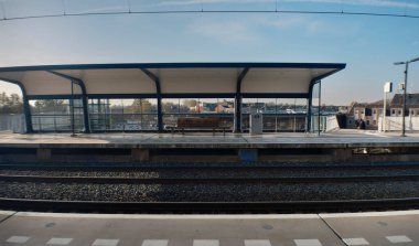 Mavi gökyüzü altında korunaklı boş demiryolu platformu (bu resim anamorfik mercekle yapılmıştır)