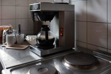 Modern mutfak tezgahına yerleştirilmiş cam sürahi ile sade kahve demleme sistemi.