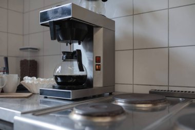 Mutfak tezgahına cam sürahi yerleştirilmiş etkin kahve makinası demleme döngüsünü gösteriyor