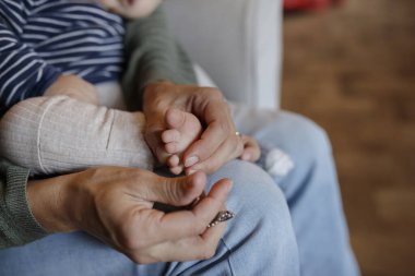 Yetişkin ellerinin mahrem anı, bebeğin küçük ayaklarını nazikçe sarmalar, özen ve bağlantı gösterir.