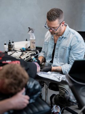 Dövme sanatçısının malzeme ve teçhizatla müşterisi üzerinde çalışmasına geniş bir bakış açısı