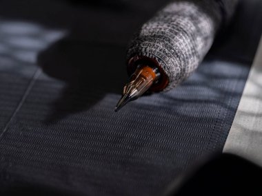 Siyah beyaz çizgili yüzey üzerinde duran kahverengi uçlu dövme makinesi kartuşu