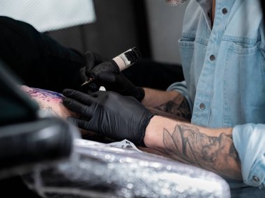 Stüdyo seansı sırasında renkli bir kol dövmesi üzerinde çalışan sanatçı.