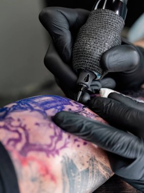 Renkli Japon peyzajının üzerine mor şablonlu dövme makinesi tutacağı ve iğne kartuş yerleştirilmiş aşırı yakın plan..