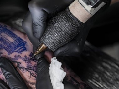 Japon pagoda mimarisi üzerinde çalışan dövme sanatçısının yakın çekimi. Mürekkep temizleme için kağıt havlu kullanılabilir..