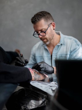 Profesyonel stüdyoda kol dövmesi üzerine yoğunlaşan dövme sanatçısı portresi..