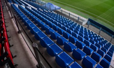 Sol tarafında kırmızı koltuklar olan mavi stadyum bankı. Anamorfik mercekle çekilmiş..