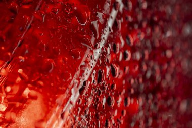 Kırmızı ışıklı su damlacıkları dikey akış modelini ve dramatik ışıklandırmayı göstererek soyut sanatsal doku oluşturur