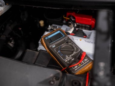Otomotiv elektriksel tanılama işlemi sırasında motor bölmesinde dijital çoklu metre test aracı bataryası