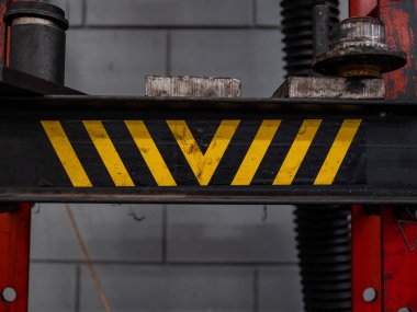 Görünür giysili endüstriyel otomotiv kaldırma ekipmanlarında yıpranmış sarı ve siyah köşegen uyarı deseni