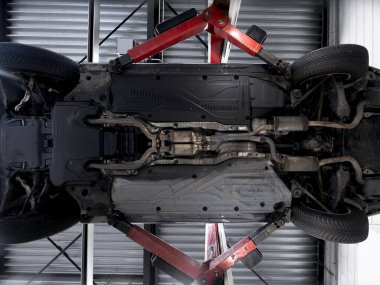 Profesyonel hizmet denetimi sırasında akü paketinin egzoz sistemini ve süspansiyon bileşenlerini gösteren elektrikli araç şasisi