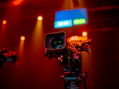 Renkli stüdyo ışıklandırma ve arka planda monitörle donatılmış sinema kamerası.