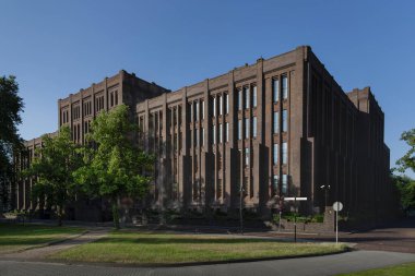 Tarihi Art Deco tuğla sanayi binası dikey pencere desenleri ve şehir parkı düzeninde süs eşyalarıyla