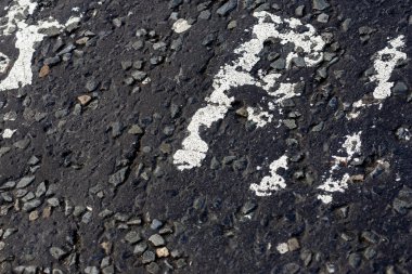 Esmer asfalt üzerinde beyaz boyalı sayılar, şehir sokaklarının doku ve bozulmasını gösteriyor.