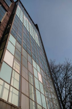 Uzun, modern, cam perdeli bir bina cephesi, aşağıdan gökyüzüne karşı ızgara deseni gösteriyor.