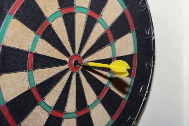 Sarı dart dart dart tahtasıyla tam ortasına isabet etti. Hassasiyet, hedef başarısı ve spor, eğlence ve iş hedefi kavramları için bar oyunu fotoğrafçılığı.