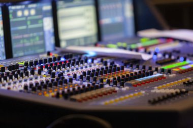 Profesyonel ses karıştırma konsolu renkli düğmeler, faderler ve LED ışıkları ile bilgisayar monitörleri. Medya ve eğlence sektörü içeriği için müzik, yayın stüdyosu ve ses mühendisliği.