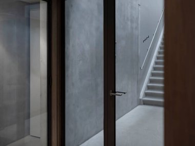 Camdan kapısı ve metal sapı olan modern beton merdiven boşluğu, duvarda minimalist merdiven sembolü