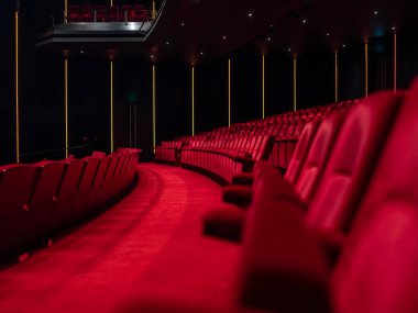 Kavisli kırmızı koltuklu modern sinema salonu, LED Strip aksan ışıkları ve görünür projeksiyon kabini