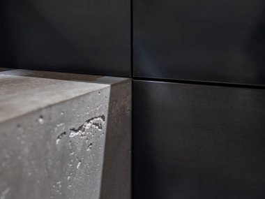 Modern mutfaktaki pürüzsüz siyah çelik dolap panellerine yakın çekim beton.