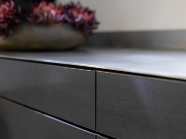 Bulanık çiçekli siyah çelik dolabın kenarı yumuşak bokeh oluşturur.