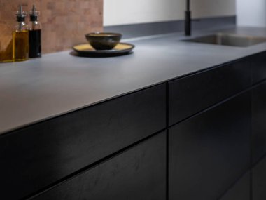 Çelik mutfak tezgahı ahşap kesim tahtası, seramik kaseler ve entegre lavabo.