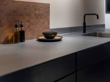 Kasap bloğu, yağ şişeleri ve seramik bulaşık takımlarıyla modern çelik mutfak çalışma alanı