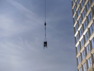 Turna kancası inşaat yükünü taşıyor, ağır kaldırma ekipmanları çalışıyor.