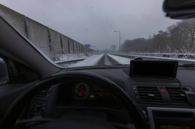 Kış boyunca karlı Hollanda otobanındaki sürücü manzarası, gösterge paneli ve karla kaplı manzaralı beton ses duvarı ile yan yana.