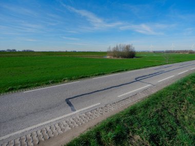 Yeşil polder manzaralı, rüzgar türbinli düz Hollanda hendek yolu.