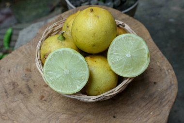 Taze sarı turunçgil meyveleri ve dokuma sepetinde taze meyve suyu veya sağlıklı beslenme kavramları için ideal ahşap bir yüzey üzerine yerleştirilmiş dilimlenmiş yarımlar..