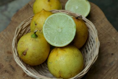 Olgun narenciye meyveleri, ahşap bir yüzeyde dokuma sepetinde ustalıkla düzenlenir. Bu da yiyecek ve sağlıklı yaşam biçimleri için kullanılacak tazelik hissini uyandırır..