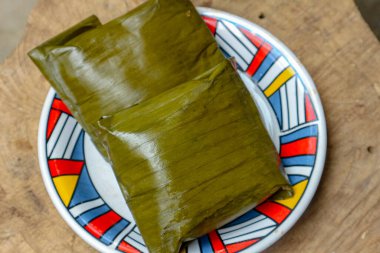 Ahşap bir yüzey üzerinde duran dekoratif bir tabakta, ev yapımı ya da geleneksel mutfağın göstergesi olan ve yemek blogları için ideal olan iki porsiyon sarılı yiyecek sunuluyor..