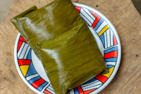 Ahşap bir yüzey üzerinde duran dekoratif bir tabakta, ev yapımı ya da geleneksel mutfağın göstergesi olan ve yemek blogları için ideal olan iki porsiyon sarılı yiyecek sunuluyor..