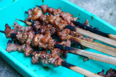 Kahverengi et şişleri açık mavi bir tepside, kısmen yanmış ahşap çubuklar ve iştah açıcı ve davetkar bir hisle, yiyecekle ilgili promosyonlar ve mutfak projeleri için ideal.