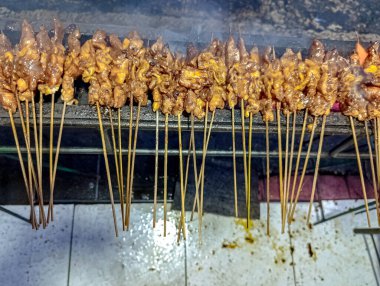 Altın kahverengi et şişleri, yükselen dumanla ızgara yapıyor ve gıda pazarlaması için lezzetli ve sıcak bir ortam yaratıyor..