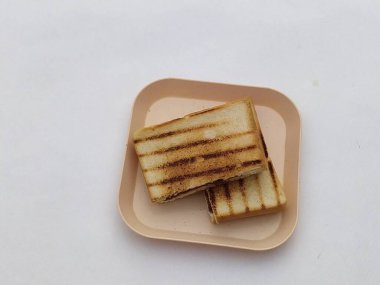 Izgara sandviç şeftali renginde bir tabakta durur, hızlı bir öğle yemeği ya da atıştırmalık için mükemmeldir..