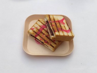 Kare bir tabakta iki ızgara ve çikolata dolgulu ve pembe şurupla servis edilir ve öğle yemeği veya atıştırmalık olarak servis edilebilir..
