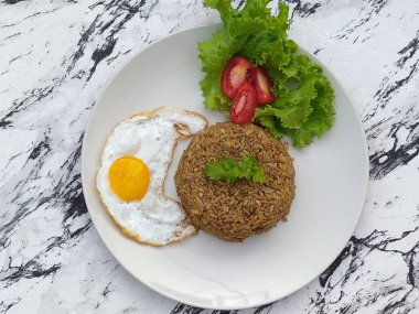 Lezzetli ve eksiksiz bir yemek için kızarmış pirinç yemeği yumurta ve salatayla servis edilir..