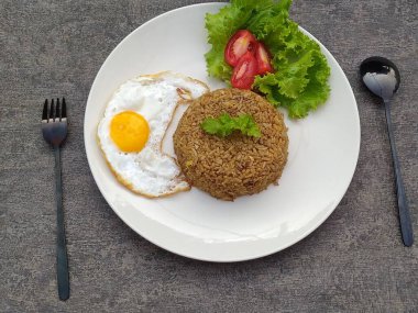 Lezzetli bir yemek için kızarmış yumurta, salata ve çatal bıçakla bir tabak pilav servis edilir..