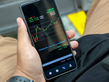 Finansal verileri, kırmızı ve yeşil çizgileri olan borsa grafiklerini ve siyah arkaplanı gösteren modern bir akıllı telefon, iş ve yatırım içeriği için analitik bir ruh hali yaratıyor..