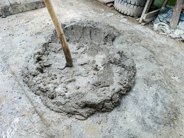 Ham malzeme ve aletleri gösteren, endüstriyel ya da DIY projeleri için uygun bir inşaat ya da inşaat süreci taşıyan, açık hava inşaat alanında ahşap çubuklu taze çimento yığını..