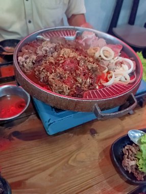 Pişmiş et dilimleri ve taze sebzelerle pişirilmiş cızırtılı bir Kore barbekü ızgarası yemek deneyimleri için mükemmel, davetkar bir ortam yaratıyor..