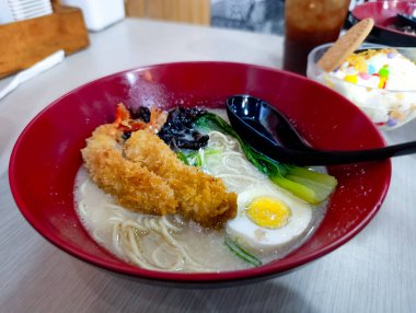 İçinde kızarmış balık fileto ve yeşil sebzelerin bulunduğu bir kase Japon eriştesi. Doğal ışıklandırmayla birlikte kaynamış yumurta ve yeşil sebzeler yemek ve yemek pazarlama için mükemmel, davetkar bir ortam yaratıyor..