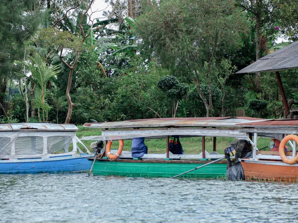Arka planda yemyeşil ağaçlar ve bitki örtüsüyle dolu bir su yolu boyunca yanaşmış iki tekne seyahat ve açık hava macera pazarlaması için mükemmel huzurlu bir doğal manzara yaratıyor..