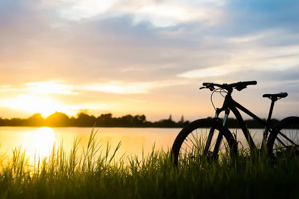 Sylwetka Mountain bike zachód słońca na rzeki — Zdjęcie stockowe