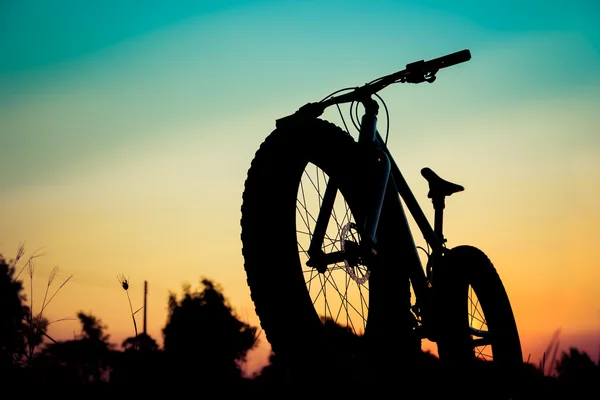 Silhouette snow bike bei schönem Sonnenuntergang, silhouette fatbike — Stockfoto