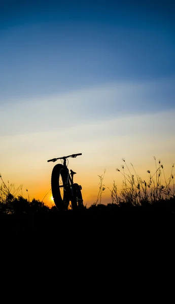 Piękny zachód słońca niebo i fatbike sylwetka, sylwetka rower śniegu — Zdjęcie stockowe