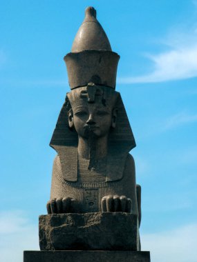 Kafasında Nemes başlığı ve açık mavi gökyüzüne karşı dizilmiş uraeus kobra sembolü olan bir insan kafası olan taş sfenks heykeli. Bu antik Mısır heykeli, sanat ve kültürü yansıtan güç, koruma ve ilahi otoriteyi temsil eder..