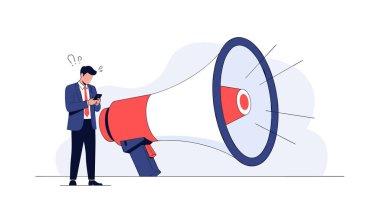 Takım elbiseli bir işadamı arka planda dev bir kırmızı ve beyaz megafonun önünde dururken cep telefonuna odaklanır..